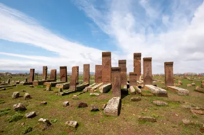 Ornately carved Seljuk tombstones standing across the grassy historic Ahlat Cemetery near Lake Van, eastern Turkey.