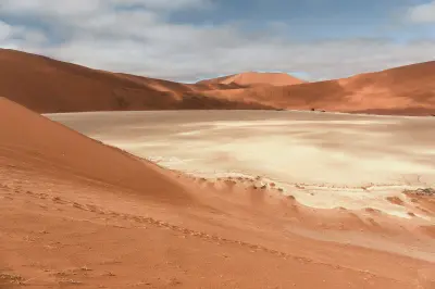 White clay pan enclosed by red sand dunes in Hiddenvlei, Namibia.