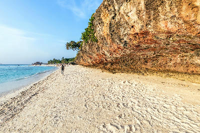Golden limestone cliffs overlooking the white sand and turquoise waters of Kendwa Beach on Zanzibar's north coast, Tanzania.