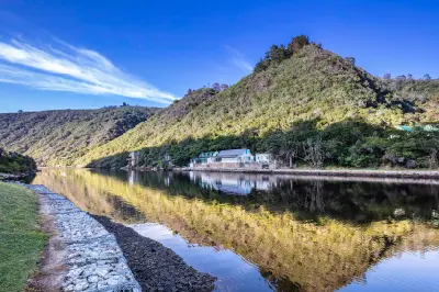 Calm waters of the Kaaimans River reflecting forested hills and riverside cottages near Wilderness on South Africa's Garden Route.