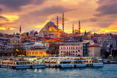 Istanbul waterfront and ferries at sunset with the Süleymaniye Mosque rising above the historic peninsula.