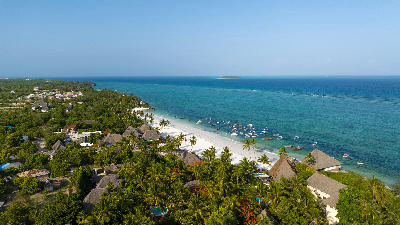 Aerial view of Matemwe Beach showing white sand, anchored boats, palm trees, and turquoise Indian Ocean waters in Zanzibar, Tanzania.