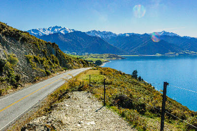 Lakeside road above Lake Hāwea with surrounding Southern Alps mountains, South Island, New Zealand.