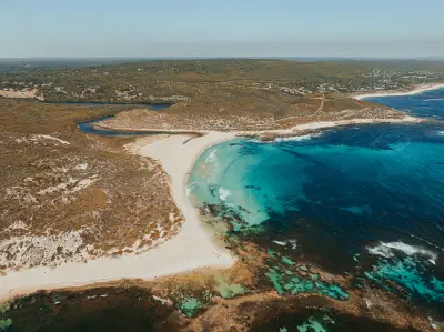 Aerial view of a white-sand beach, turquoise water and coastal heath along the Margaret River coast in Western Australia.