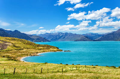 Curving shoreline of Lake Hāwea with turquoise water and surrounding mountains, Otago, South Island, New Zealand.