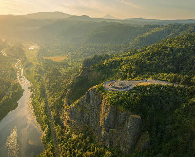 Vista House at Crown Point in the Columbia River Gorge, Oregon USA, with aerial view of cliffs, river valley, and forest at golden hour.