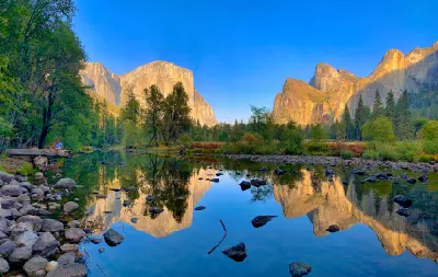 Valley View Yosemite with El Capitan and Bridalveil Fall reflected in the Merced River with rocks and trees in foreground.