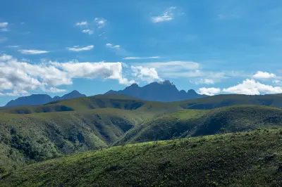 Rolling green hills and distant mountain peaks in the Baviaanskloof Wilderness Area under dramatic clouds, Eastern Cape, South Africa.