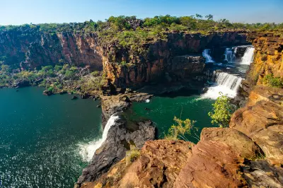 Multi-tiered Mitchell Falls cascade over rugged sandstone cliffs into deep turquoise pools on the Mitchell Plateau.