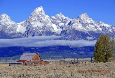 Moulton Barn with snow-capped Teton Range and low cloud layer in the background, Mormon Row, Grand Teton National Park, Wyoming, USA.