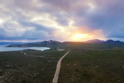 Aerial view of a road through Cape Le Grand National Park with coastal heath, granite mountains and Lucky Bay in Western Australia.