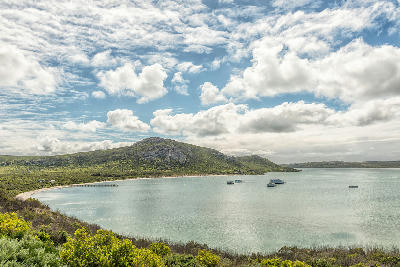 Panoramic view of Kraalbaai on Langebaan Lagoon with houseboats, jetty and granite hills in West Coast National Park, South Africa.
