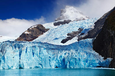 Spegazzini Glacier ice wall with steep mountain backdrop and glacial lake in Patagonia, Argentina.