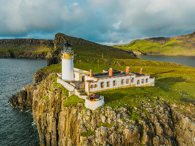 Aerial view of Neist Point Lighthouse on the Isle of Skye, showing the lighthouse, cliffs, and surrounding coastline in Scotland.