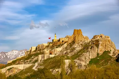 Ancient stone walls and ruins of Van Castle covering a rocky ridge, with snow-capped mountains in the background, eastern Turkey.