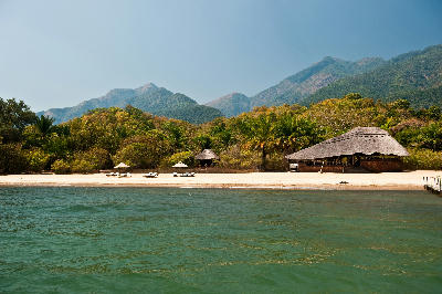 Safari lodge on the sandy shores of Lake Tanganyika with the forested Mahale Mountains rising behind in western Tanzania.