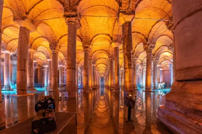 Symmetrical rows of illuminated stone columns and arches reflected in the water inside the Basilica Cistern, Istanbul, Turkey.