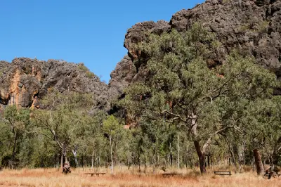 Picnic tables beneath eucalyptus trees and rugged limestone cliffs at the start of the Tunnel Creek Walk.