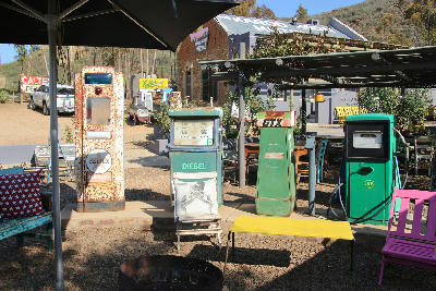 Old decorative fuel pumps and outdoor seating at a vintage-style roadside restaurant in Barrydale on Route 62, Western Cape, South Africa.