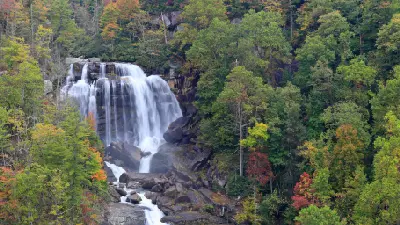 Telephoto view of Upper Whitewater Falls surrounded by colourful forest in Nantahala National Forest, North Carolina.