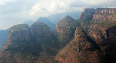 The Three Rondavels rock formations overlooking the Blyde River Canyon in Mpumalanga, South Africa, with layered sandstone cliffs and rugged canyon landscapes in the background.