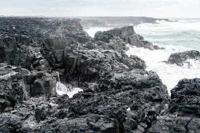Waves breaking against dark basalt cliffs on the Reykjanes Peninsula coast, Iceland.