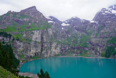 Oeschinen Lake surrounded by steep cliffs and waterfalls with turquoise water in the Bernese Oberland, Switzerland