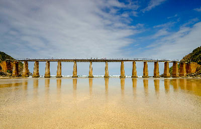 Historic Kaaimans Railway Bridge reflected in wet sand at low tide where the Kaaimans River meets the Indian Ocean near Wilderness on South Africa's Garden Route.