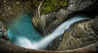 Close-up of Trümmelbach Falls cascading into a turquoise pool within a narrow rock gorge in Lauterbrunnen Valley, Switzerland.