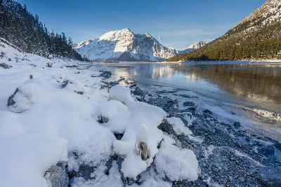 Lower Kananaskis Lake with snowy shoreline and mountains in Alberta, Canada.