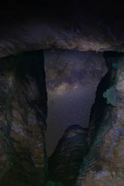 Milky Way and dense stars framed by the towering dark sandstone walls of Cathedral Gorge at night.