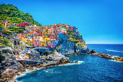 Colourful buildings stacked on steep hills above the Mediterranean Sea in Cinque Terre, showing traditional Italian architecture.
