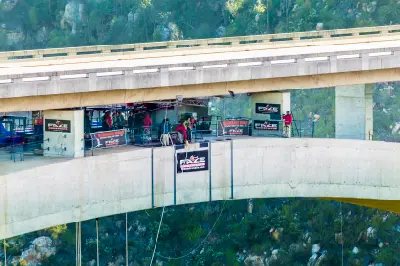Close-up view of the Bloukrans Bungy platform suspended beneath Bloukrans Bridge in South Africa, with staff and jumpers preparing above the deep river canyon.