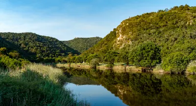 The Touw River winding through forested hills at Ebb and Flow Camp in Wilderness, with calm waters reflecting indigenous vegetation along South Africa's Garden Route.