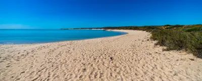Wide sandy beach and calm turquoise water at Turquoise Bay in Cape Range National Park.
