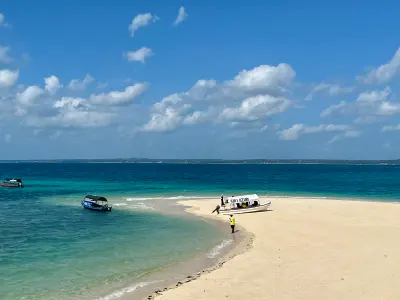 Traditional boats moored beside the white sand beach and turquoise waters of Prison Island near Stone Town, Zanzibar.