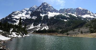 Crater Lake near Aspen Colorado below the Maroon Bells with alpine lake, rocky shoreline, and snow-covered peaks in the Elk Mountains.
