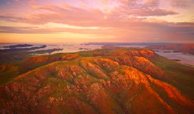 Aerial sunrise view across the rugged red hills, islands and vast waterways of Lake Argyle in the Kimberley.