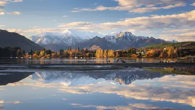 Reflections of the Southern Alps and Wanaka township in calm pools along the shoreline of Lake Wanaka, South Island, New Zealand.