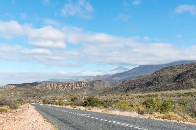 Route 62 crossing open Klein Karoo shrubland with rugged hills and distant mountain ranges between Calitzdorp and Ladismith, Western Cape, South Africa.