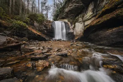 Long exposure photograph of Looking Glass Falls surrounded by layered rock walls and forest in Pisgah National Forest, North Carolina.