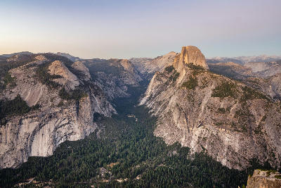 View from Glacier Point in Yosemite National Park showing Half Dome, granite cliffs, and forested Yosemite Valley at dusk.