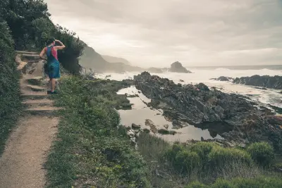 Hiker on a coastal trail above the rocky shoreline of Tsitsikamma National Park on South Africa's Garden Route