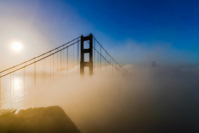 Golden Gate Bridge tower emerging through sea fog at sunrise from Battery Spencer