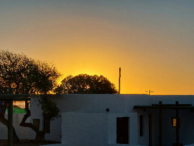 Whitewashed building at Elands Bay during sunset, with the sky glowing gold behind silhouetted trees near Baboon Point on South Africa's West Coast.