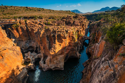 Wide view of Bourke’s Luck Potholes in Mpumalanga, South Africa, showing sculpted sandstone formations, deep water-filled potholes, narrow gorges and visitor walkways above the canyon.