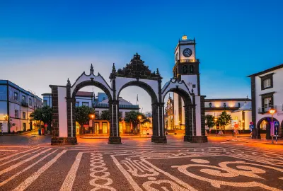 Historic Portas da Cidade city gates and clock tower illuminated at dusk in Ponta Delgada, São Miguel Island, Azores.