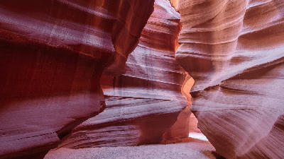 Interior of Upper Antelope Canyon in Arizona showing smooth curved red sandstone walls and a narrow slot canyon passage with soft reflected light.