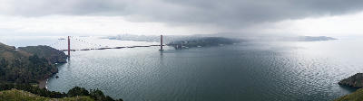 Wide view of the Golden Gate Bridge and San Francisco skyline from Hawk Hill under storm clouds