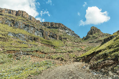 Rocky mountain track on the upper slopes of Sani Pass surrounded by steep cliffs and alpine terrain in the Drakensberg Mountains between South Africa and Lesotho.
